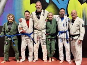 Adult students wearing newly awarded blue belts at Straight Blast Gym Calgary, post-promotion photo.